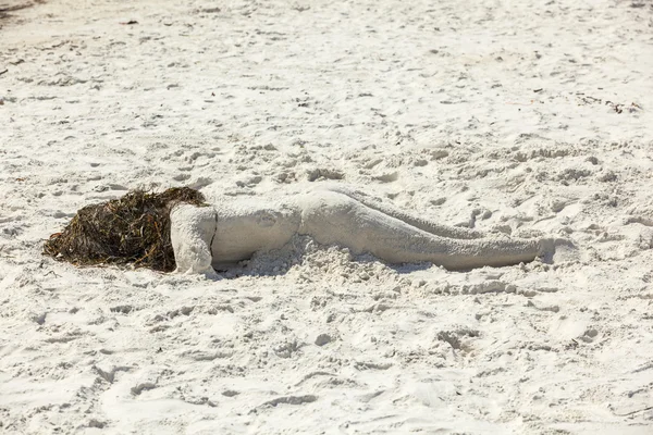 Mulher deitada na praia formada com areia — Fotografia de Stock