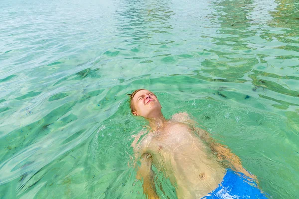 Handsome teen has fun playing dead mens float in the ocean — Stock Photo, Image