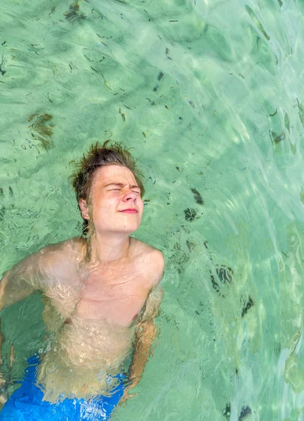 Pohledný teen má zábava hrát mrtvého Pánská plavat v oceánu — Stock fotografie