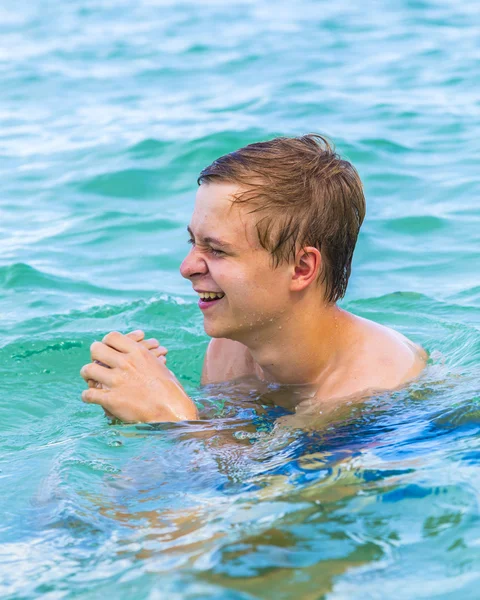 Tizenéves fiú élvezi az óceán és laughes úszás — Stock Fotó
