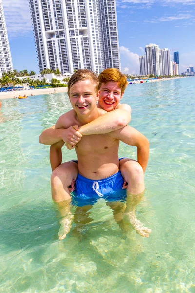 Brothers have joy playing piggyback in the clear ocean — Stock Photo, Image