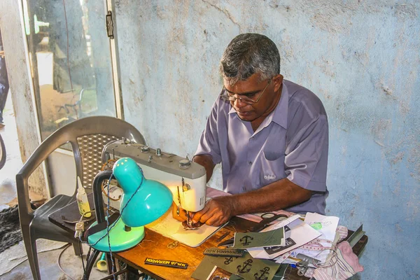 Tailor at the market is sewing name badges for customers — Stock Photo, Image