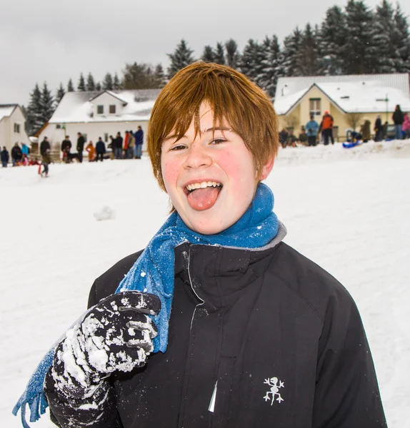 Niño con el pelo rojo parece feliz de jugar en la nieve — Foto de Stock