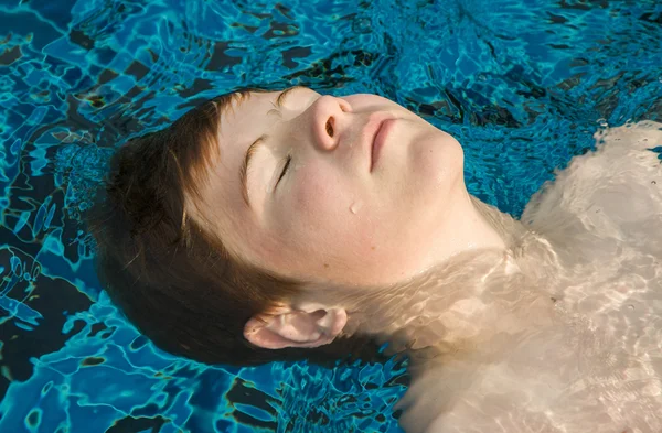 Boy enjoys floating on his back — Stockfoto