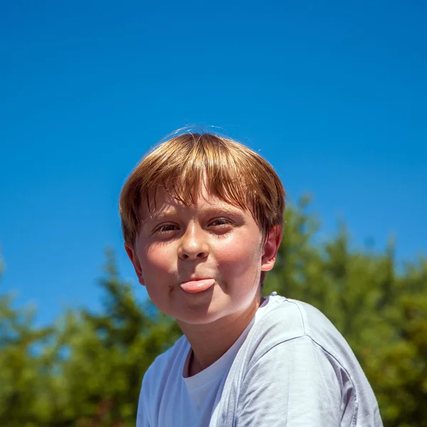 Menino feliz está sorrindo e mostrando sua língua — Fotografia de Stock