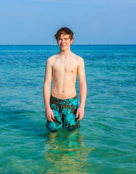 Jovem rapaz está de pé no belo mar claro e goza do — Fotografia de Stock