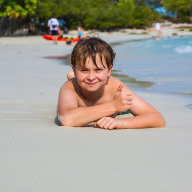 Çocuk sahilde yatan ve suyun sıcaklığını tadını ve kendinden emin ve mutlu seyir