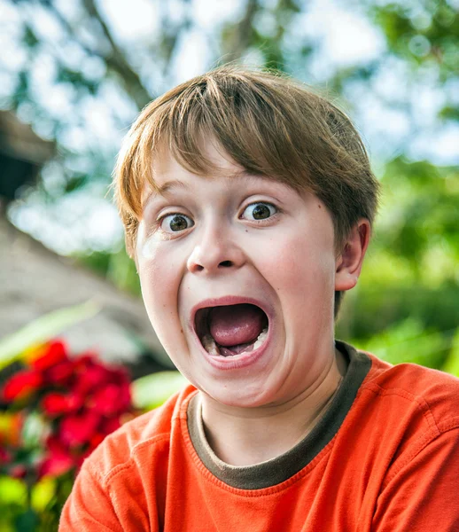 Jovem menino faz caras engraçadas — Fotografia de Stock