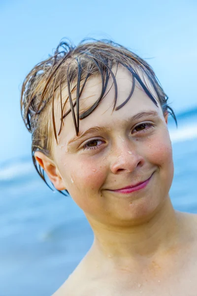 Menino bonito com cabelo molhado na praia — Fotografia de Stock