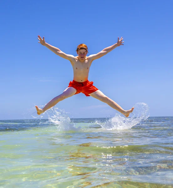 Szczęśliwy chłopiec skacze w powietrzu nad oceanem — Stok fotoğraf