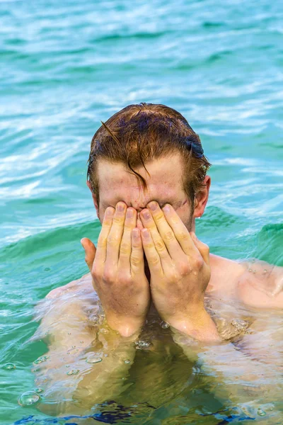 Teenage boy cleans eyes of saltwater — Stock Photo, Image