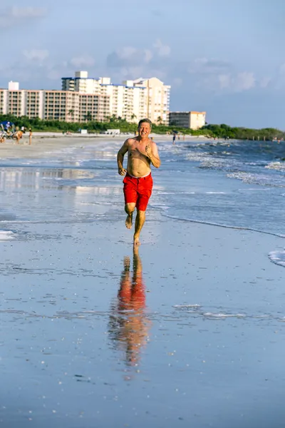 男は、ビーチに沿ってジョギングを楽しんでいます — ストック写真