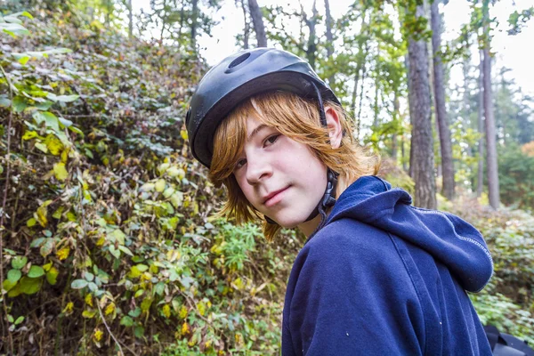 Ung tonårspojke i skogen med cykel hjälm — Stockfoto