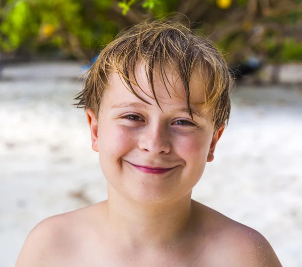 Lycklig pojke med blött hår på stranden — Stockfoto