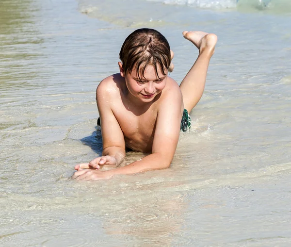 Çocuk sahilde yatıyor ve kuma haddeleme sahiptir