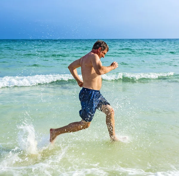 Uomo corre lungo la bellissima spiaggia — Foto Stock