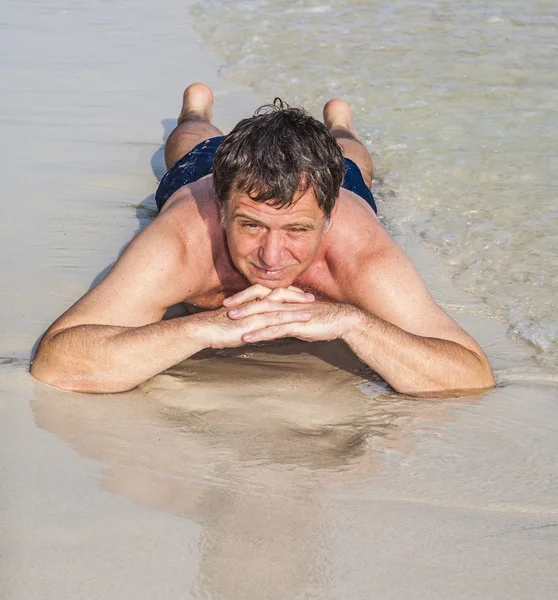 Mannen i bathingsuit ligger på stranden — Stockfoto