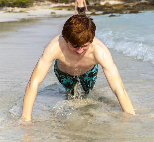 Jongen op het prachtige strand treinen push-ups — Stockfoto