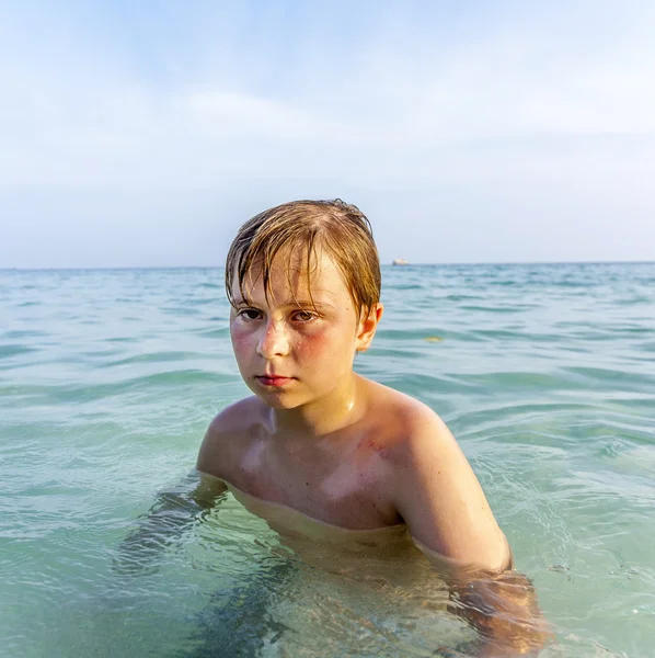 Сердитий молодий хлопчик плаває у прозорій теплій воді — стокове фото