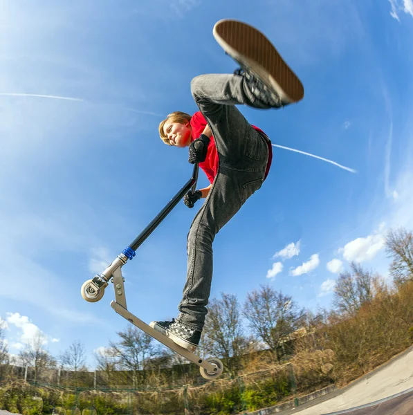 Chlapec skákání s skútr — Stock fotografie