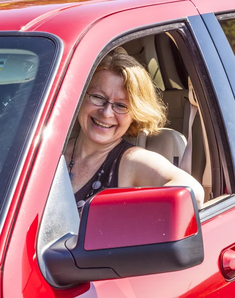 Leende kvinna kör en röd bil — Stockfoto