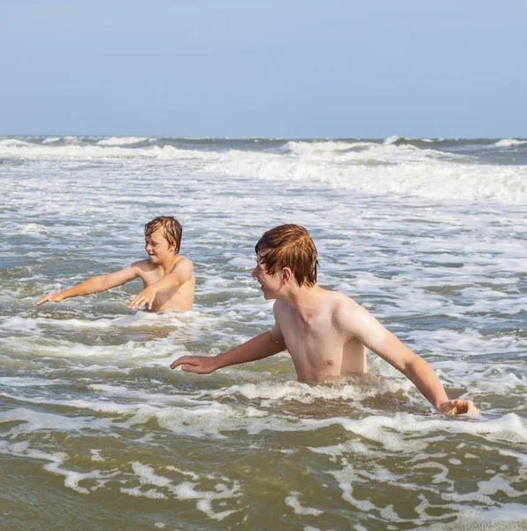Мальчики наслаждаются волнами в диком океане — стоковое фото