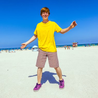 Çocuk kumsalda havada atlama sahiptir.