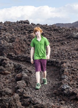Boy walking in volcanic area clipart
