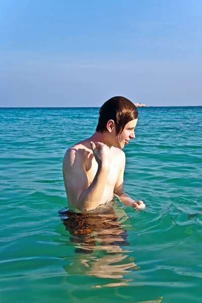 Pojken har det varma vattnet på den vackra stranden — Stockfoto