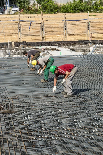 Рабочие выполняют строительство стальных прутков на строительной площадке — стоковое фото
