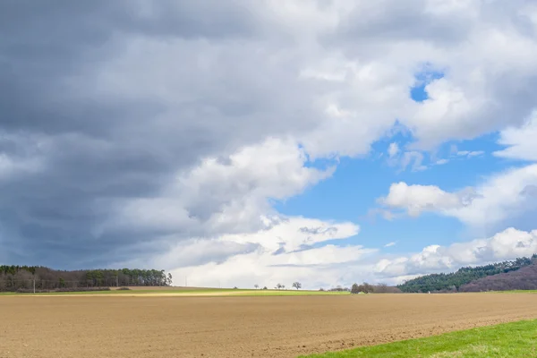 Donkere wolken en blauwe hemel over velden — Stockfoto