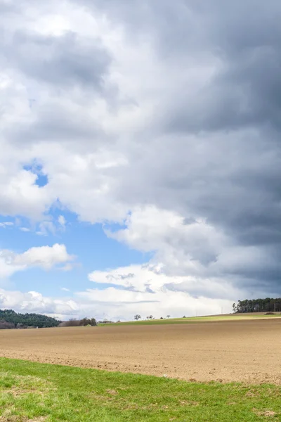 Dark clouds and blue sky over field — Stock Photo, Image