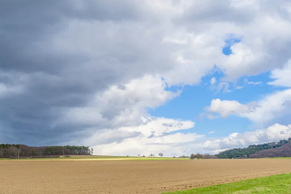 Dunkle Wolken und blauer Himmel über Feldern — Stockfoto