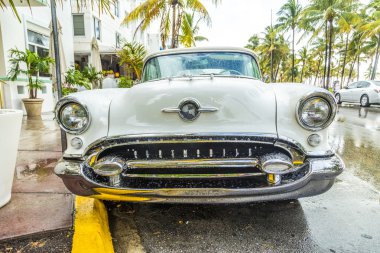 classic Oldsmobile with chrome radiator grill parked in front o clipart