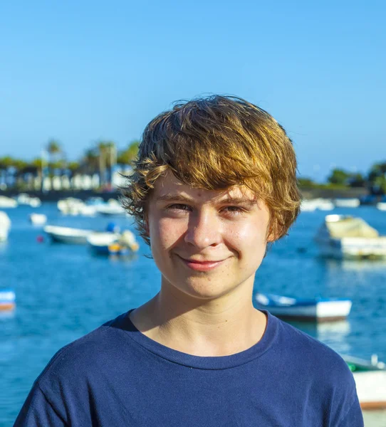 Knappe gelukkig lachend jongen met een haven op achtergrond — Stockfoto