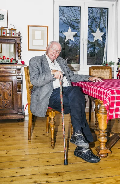 Old Grandfather sitting with his walking stick at the table — Stock Photo, Image