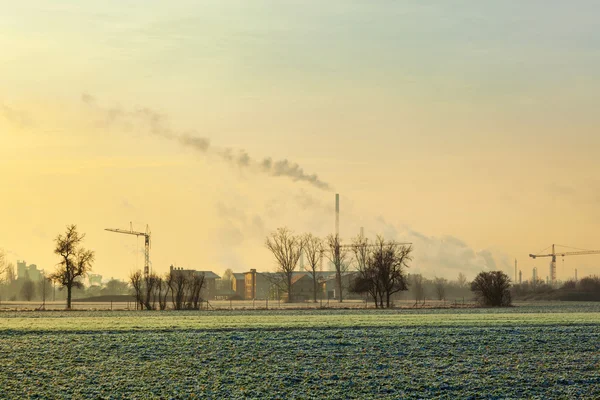 Nascer do sol na aerea rural no inverno com chaminés fumantes — Fotografia de Stock