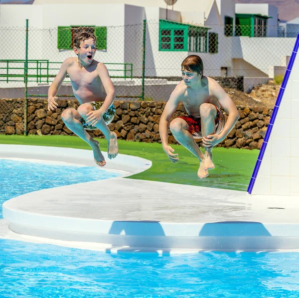 Twee vrienden springen in het zwembad — Stockfoto