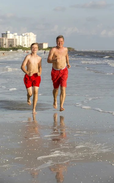 Vater und Sohn joggen gern am Strand entlang — Stockfoto