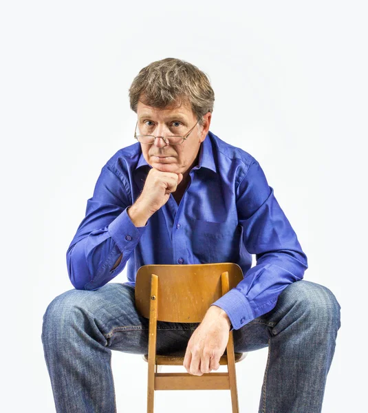 Az ember ül egy kis, fából készült szék és jelent — Stock Fotó