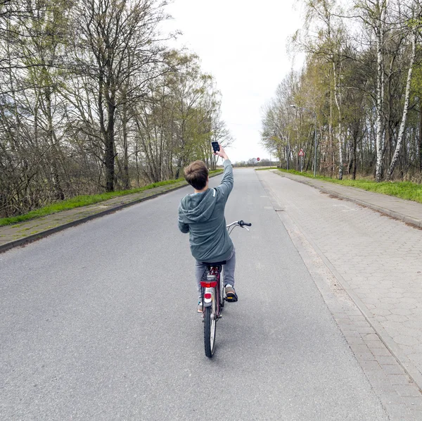 Boy shoots a picture while riding bike — Stockfoto