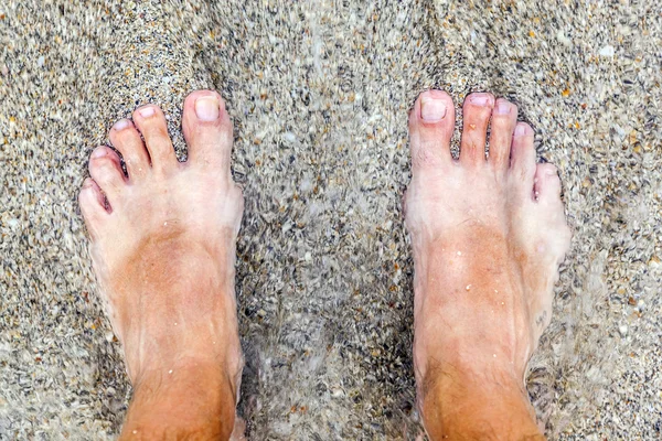 Voeten van man op het strand — Stockfoto