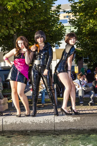 Three girls in black in costume pose at frankfurt international — Stock Photo, Image