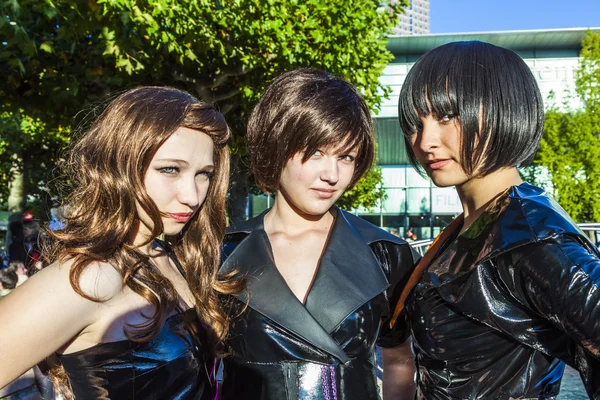 Three girls in black in costume pose at frankfurt international — Stock Photo, Image