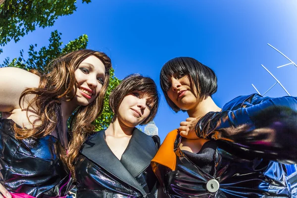 Three girls in black in costume pose at frankfurt international — Stock Photo, Image