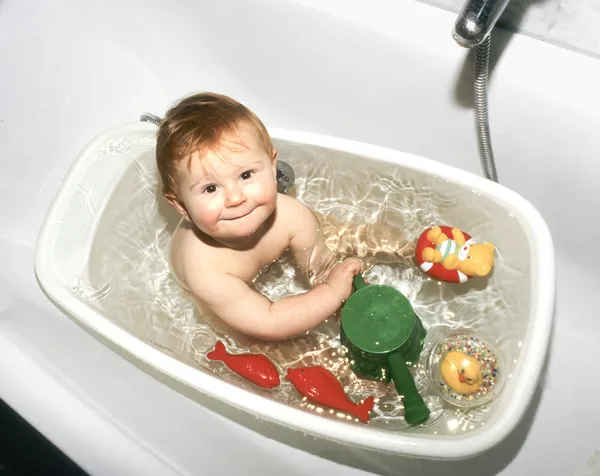 Ребенок играет в своей пластиковой ванне — стоковое фото