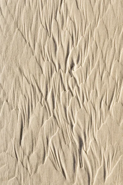 L'eau forme des motifs spectaculaires à la plage de sable fin — Photo