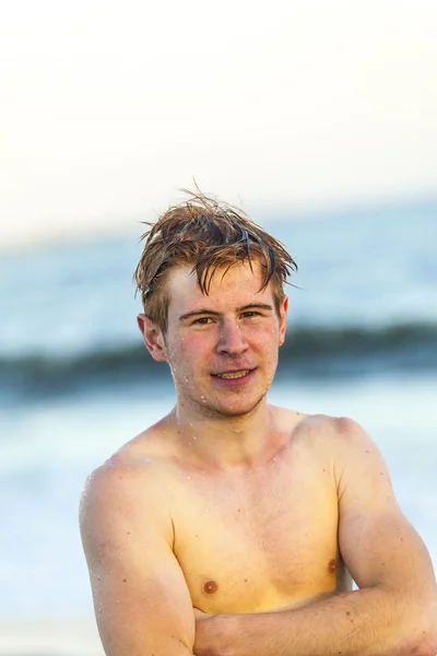 Knappe tiener op het strand in zonsondergang — Stockfoto