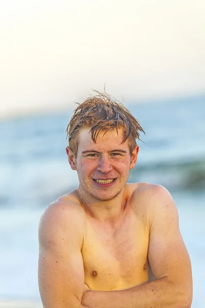 Knappe tiener op het strand in zonsondergang — Stockfoto