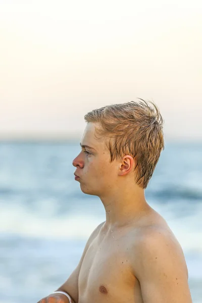 Knappe tiener op het strand in zonsondergang — Stockfoto